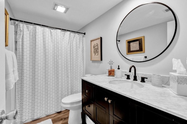 bathroom with hardwood / wood-style flooring, vanity, walk in shower, and toilet