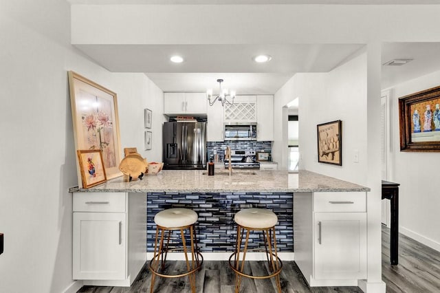 kitchen featuring light stone counters, a breakfast bar, white cabinets, and appliances with stainless steel finishes