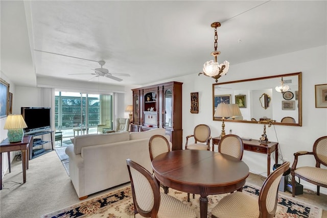 carpeted dining area with ceiling fan with notable chandelier