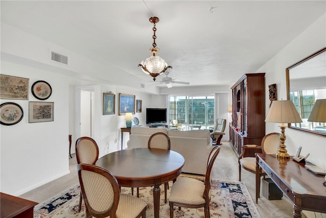 dining area featuring visible vents, baseboards, light colored carpet, and a ceiling fan