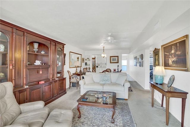 living area with light carpet, visible vents, and ceiling fan