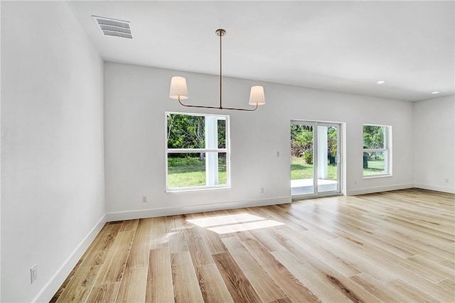 spare room featuring light wood-type flooring, visible vents, plenty of natural light, and baseboards