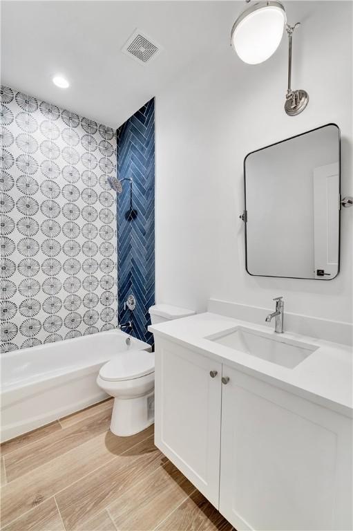 bathroom featuring visible vents, wood finished floors, toilet, and shower / washtub combination