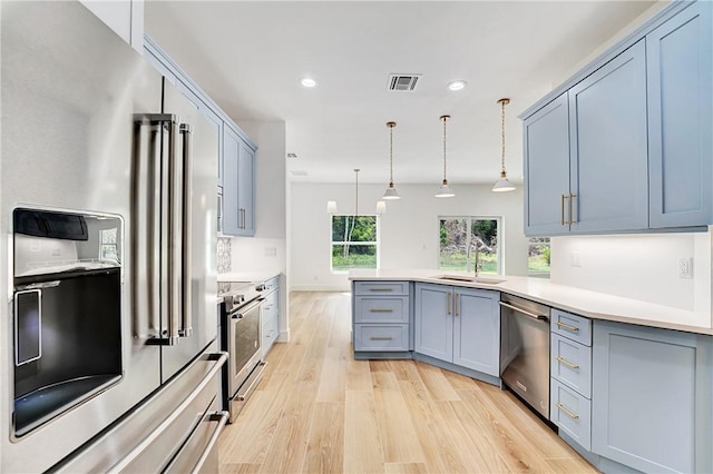 kitchen featuring visible vents, a peninsula, gray cabinetry, a sink, and appliances with stainless steel finishes