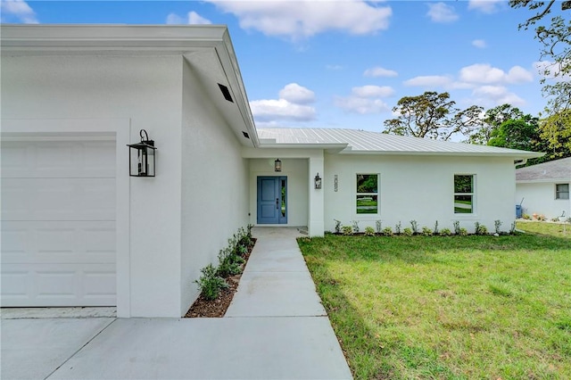 entrance to property with stucco siding, a lawn, and metal roof