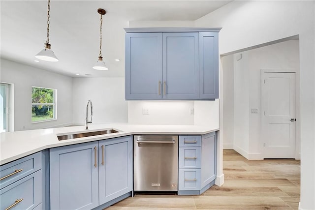 kitchen featuring light countertops, pendant lighting, light wood-type flooring, and a sink