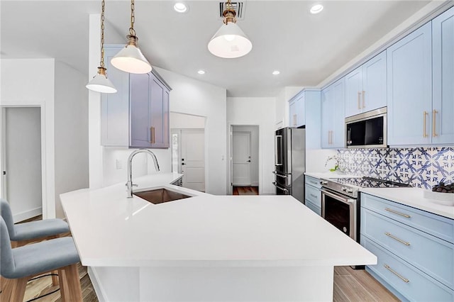 kitchen featuring visible vents, a sink, stainless steel appliances, a peninsula, and light wood finished floors