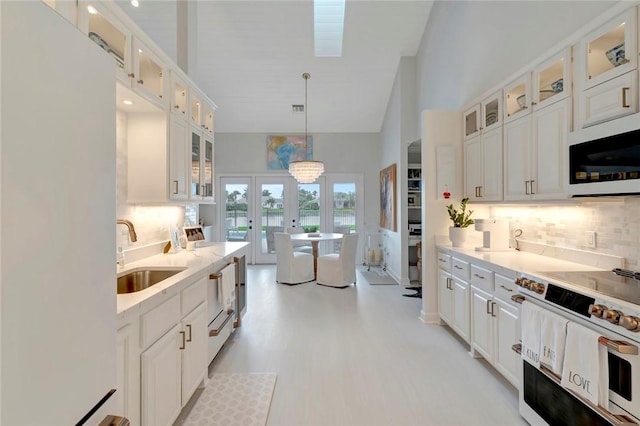 34 Cache Cay Dr, Vero Beach, FL 32963 - kitchen with a sink, white appliances, french doors, decorative backsplash, and high vaulted ceiling