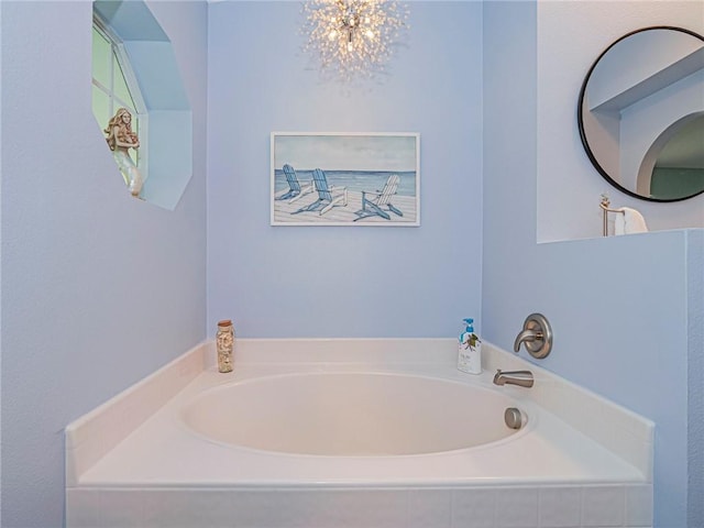 bathroom with tiled bath and a chandelier