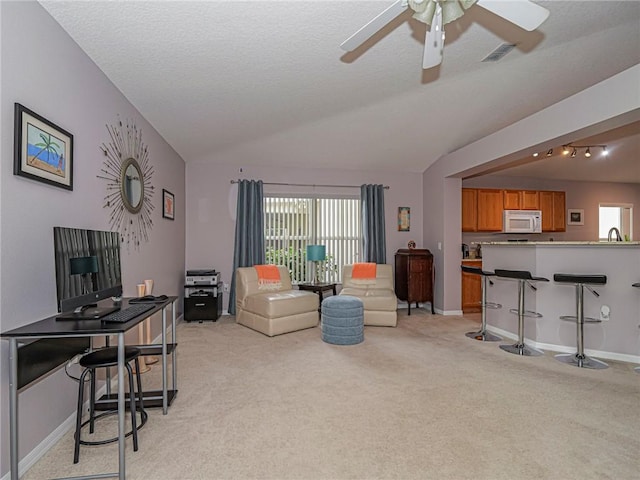 living room with a healthy amount of sunlight, sink, vaulted ceiling, and light carpet