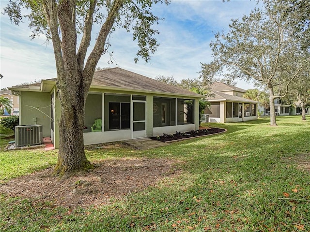 rear view of property featuring central AC unit, a lawn, and a sunroom