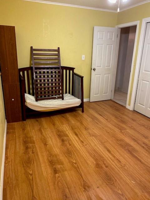 bedroom featuring crown molding and light hardwood / wood-style flooring