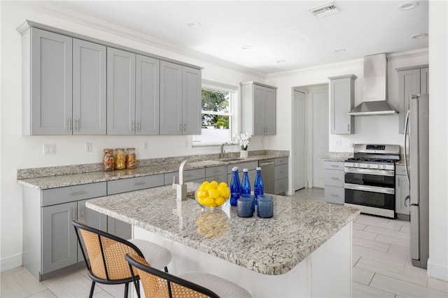 6225 S US Highway 1, Grant Valkaria, FL 32949 - kitchen featuring appliances with stainless steel finishes, wall chimney range hood, gray cabinetry, a kitchen island, and a kitchen breakfast bar