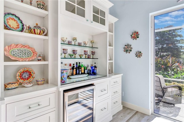 bar featuring wine cooler, white cabinetry, and light wood-type flooring