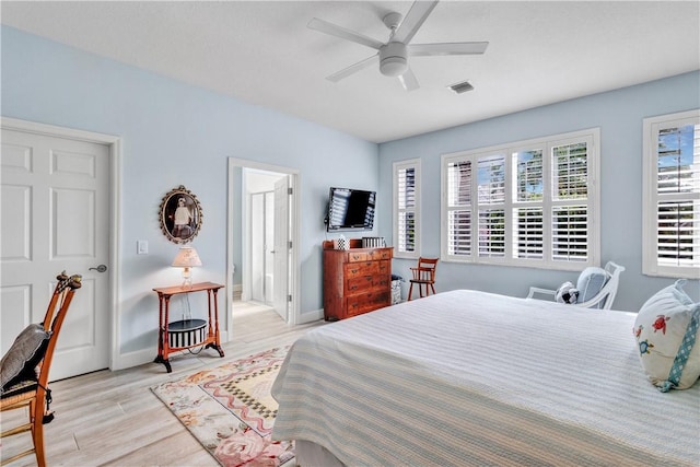 bedroom with ceiling fan, light wood-type flooring, and connected bathroom