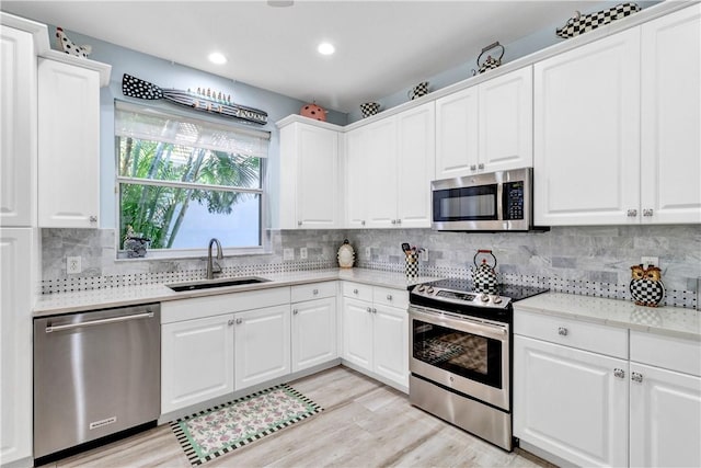 kitchen featuring sink, white cabinets, stainless steel appliances, and light hardwood / wood-style flooring