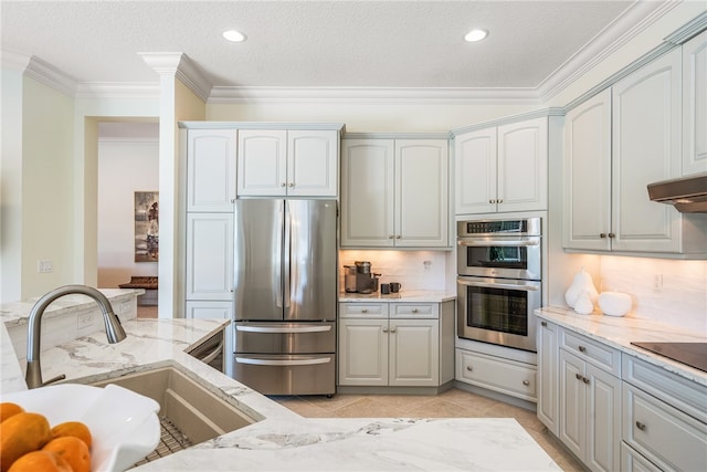 kitchen with stainless steel appliances, a sink, light stone countertops, tasteful backsplash, and crown molding