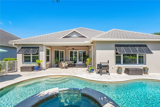 rear view of property featuring an outdoor hangout area, a pool with connected hot tub, a ceiling fan, stucco siding, and a patio area