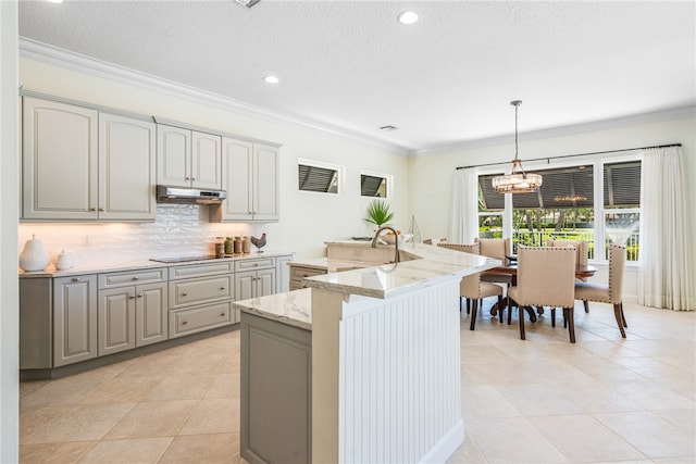 kitchen featuring a kitchen island with sink, ornamental molding, and gray cabinets