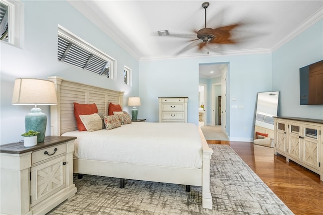 bedroom featuring baseboards, visible vents, ornamental molding, and wood finished floors