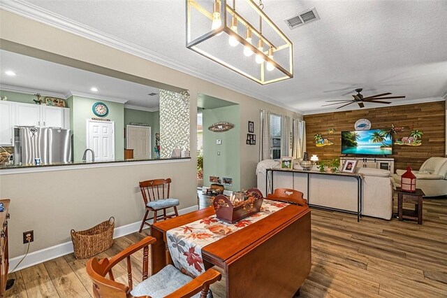 7720 15th Ln, Vero Beach, FL 32966 - dining space with visible vents, wood walls, wood finished floors, ceiling fan, and ornamental molding