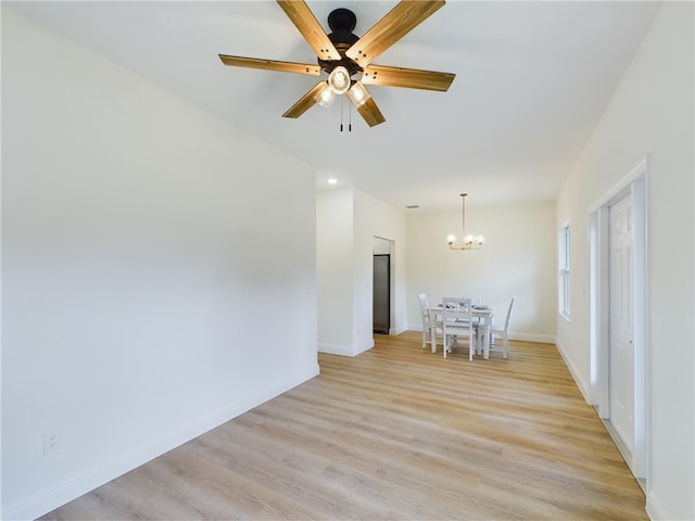 empty room with ceiling fan with notable chandelier and light wood-type flooring