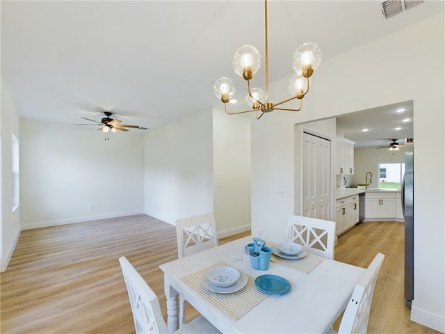 dining area featuring ceiling fan with notable chandelier, sink, and light hardwood / wood-style flooring