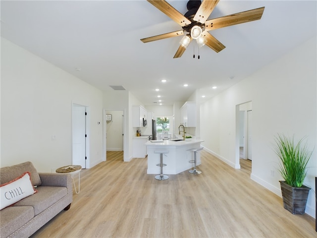 living room with ceiling fan, sink, and light hardwood / wood-style flooring