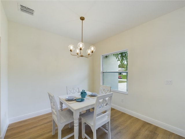 dining room with hardwood / wood-style floors and an inviting chandelier