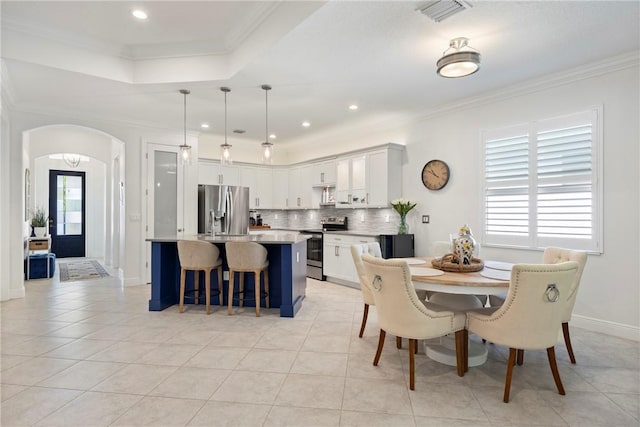 dining area featuring light tile patterned floors, a raised ceiling, a wealth of natural light, and ornamental molding