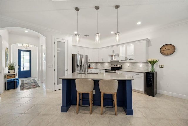 kitchen featuring tasteful backsplash, stainless steel appliances, a kitchen island with sink, sink, and white cabinets