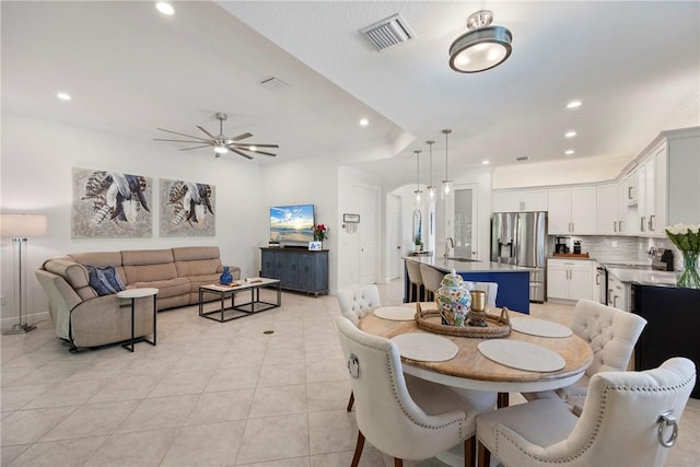 tiled dining room with ceiling fan and sink