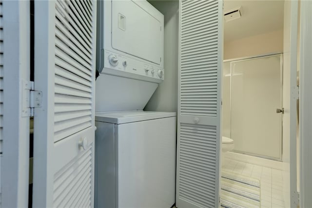 laundry area with tile patterned flooring and stacked washer / drying machine