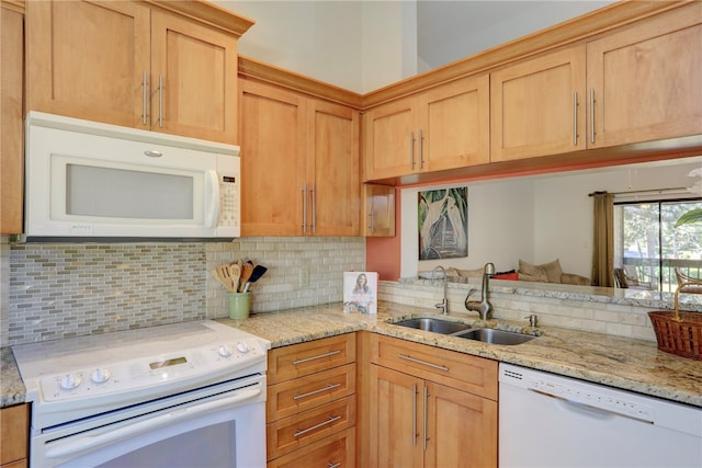 kitchen with light stone countertops, white appliances, tasteful backsplash, and sink