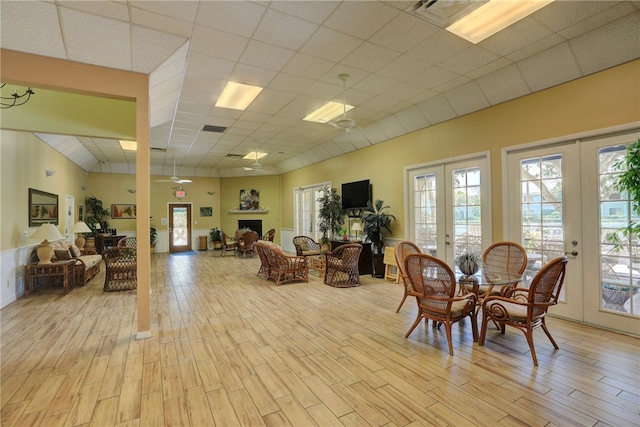 dining space with french doors, light wood-type flooring, and a paneled ceiling