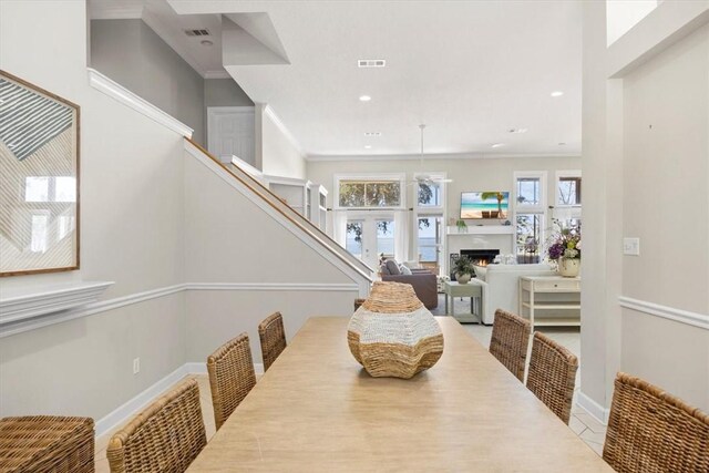 449 S Garcon Point Rd Fl, Milton, FL 32583 - dining space featuring a warm lit fireplace, stairs, crown molding, and recessed lighting