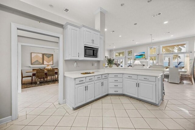 449 S Garcon Point Rd Fl, Milton, FL 32583 - kitchen with light countertops, a peninsula, black microwave, light tile patterned floors, and white cabinetry