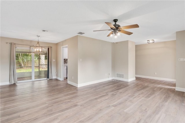 unfurnished room featuring ceiling fan with notable chandelier and light wood-type flooring