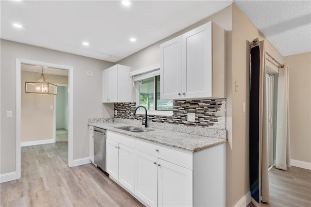 kitchen with light hardwood / wood-style floors, light stone countertops, white cabinets, stainless steel dishwasher, and sink