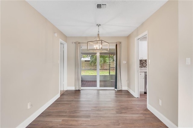 unfurnished dining area with a chandelier and dark wood-type flooring