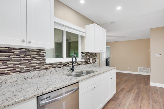 kitchen with light stone counters, dishwasher, backsplash, white cabinets, and sink