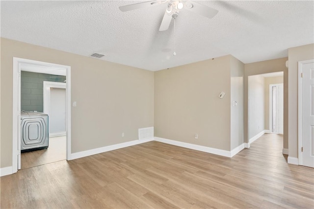 empty room featuring washer / dryer, a textured ceiling, ceiling fan, and light hardwood / wood-style floors