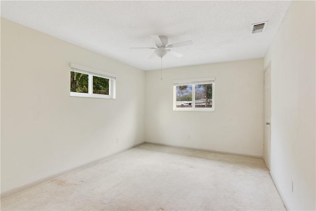 empty room featuring ceiling fan, light carpet, and a textured ceiling