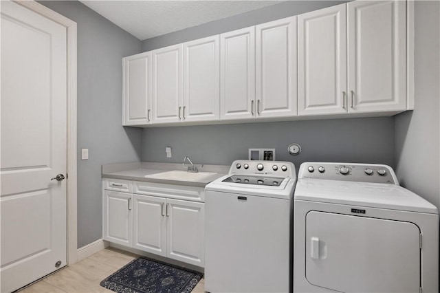 laundry area featuring a sink, baseboards, cabinet space, and independent washer and dryer