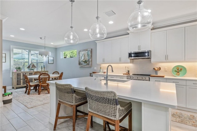 kitchen featuring ornamental molding, a sink, stove, stainless steel microwave, and backsplash