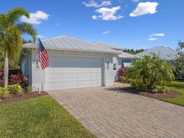 view of front of property with stucco siding, a standing seam roof, decorative driveway, an attached garage, and metal roof