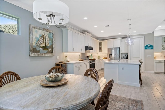 dining space with light wood finished floors, visible vents, crown molding, baseboards, and recessed lighting