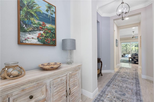 hallway featuring a notable chandelier, crown molding, and baseboards