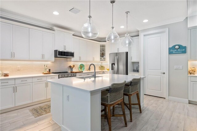 kitchen with visible vents, an island with sink, a sink, stainless steel appliances, and tasteful backsplash