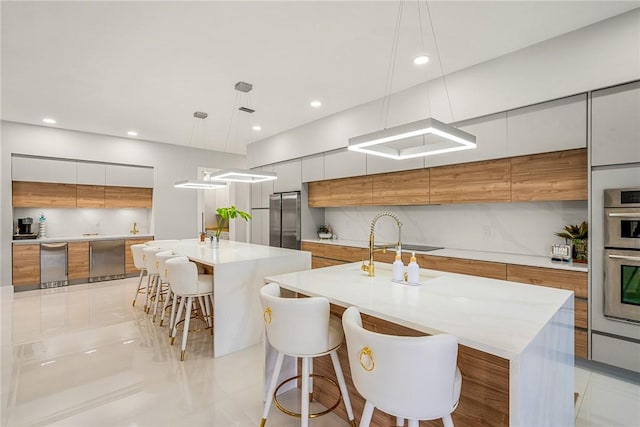 kitchen with brown cabinetry, light countertops, stainless steel appliances, a large island, and modern cabinets